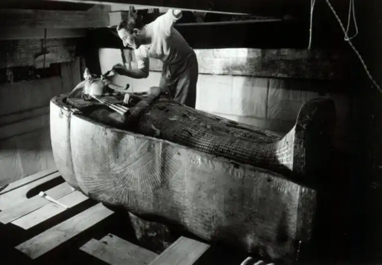 Howard Carter examining the golden shrine inside Tutankhamun's tomb, photographed by Harry Burton in the 1920s